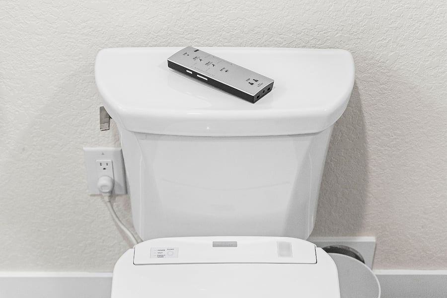 Updated toilet with a modern warm-water bidet attachment for added comfort.