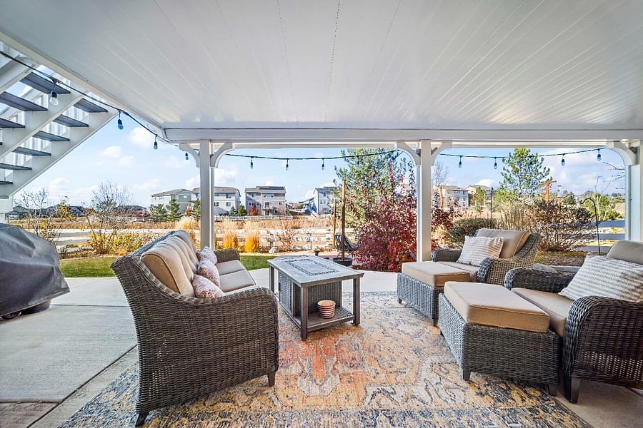 Covered private patio with comfortable seating and views of the landscaped greenbelt.