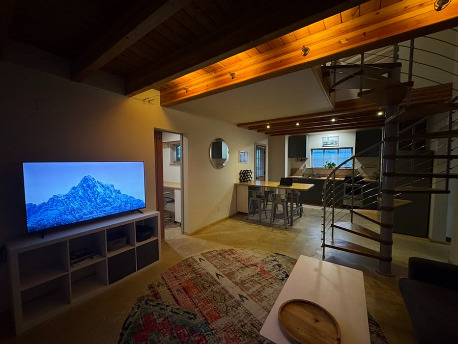 living room with spiral stair to second floor, and office room through door to the left