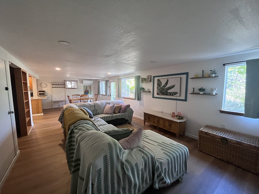 Living room (view from the bed room doors) with updated art and waterproof couch covers provided for tenants with pets or small children. Tenants have the option of a smart TV OR art work if they would rather keep the space "screen free."