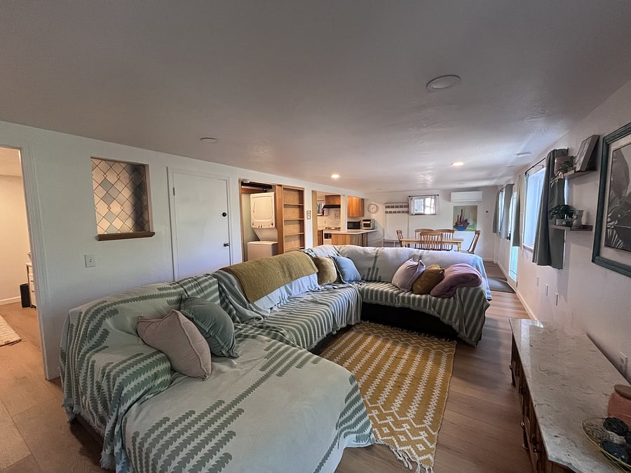 Living room (view from the corner) showing waterproof couch covers provided for tenants with pets or small children. Tenants have the option of a smart TV OR art work if they would rather keep the space "screen free."