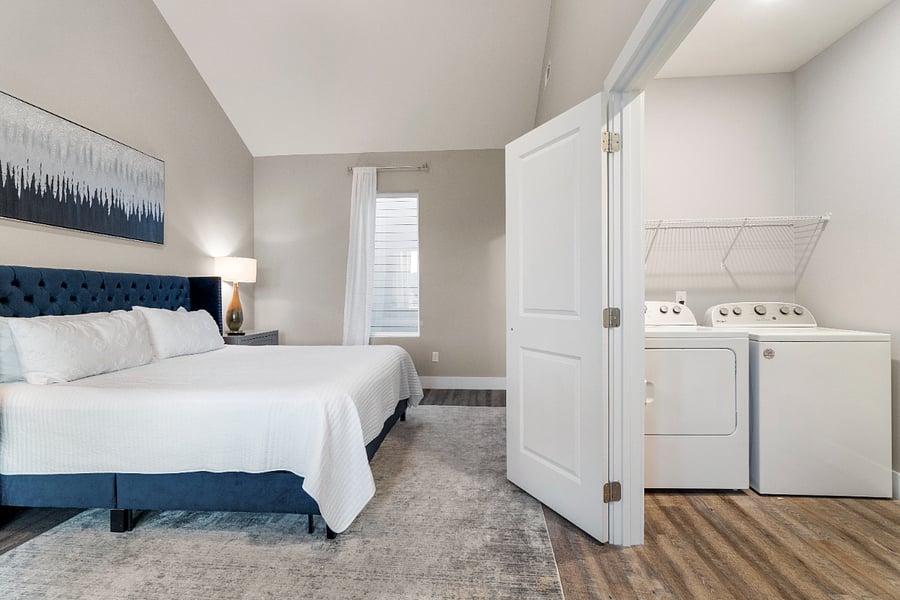 A spacious primary bedroom with a king-sized bed conveniently located right next to the in-unit laundry roommaking mid-term living easy and efficient