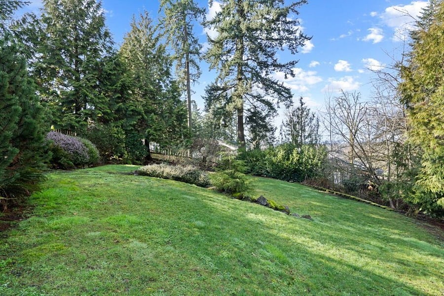Large backyard with trees all around and community fire pit below.