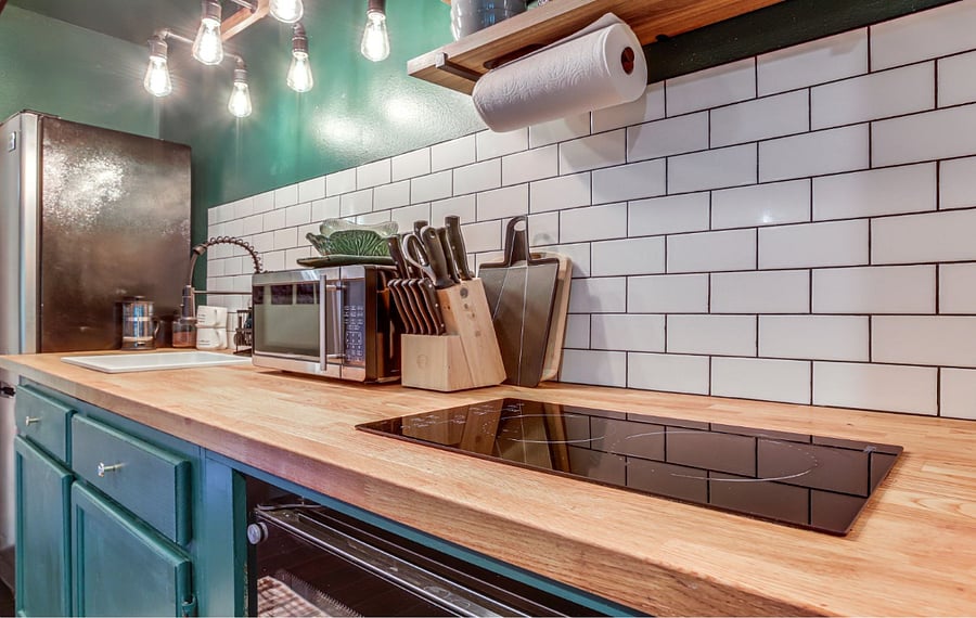 Kitchen has small sink, all cleaners, small microwave, french press, dishes and storage below with pots and pans. cooktop is electric with a convection oven below.