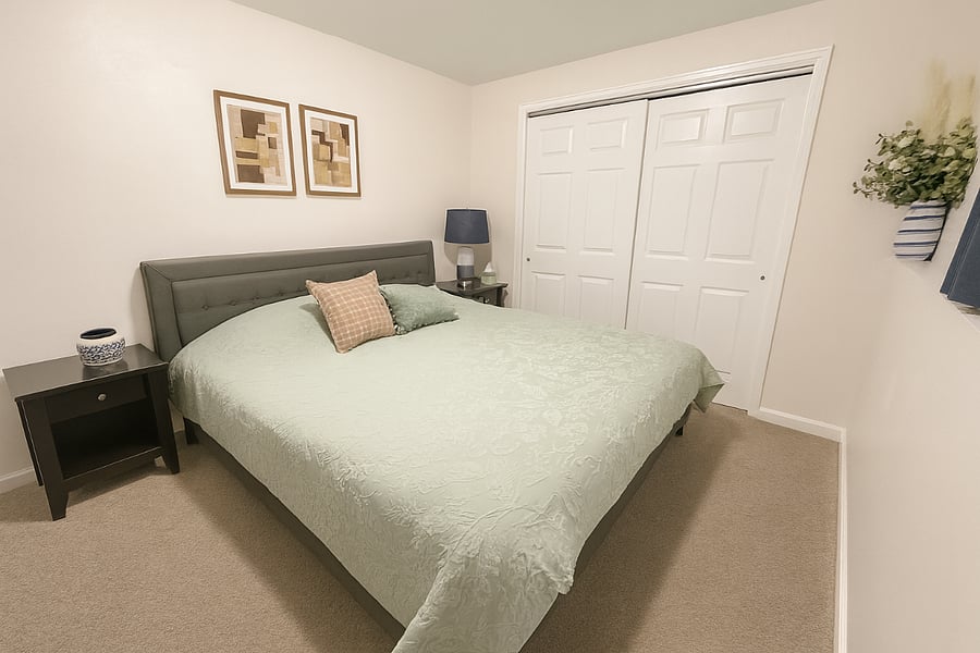 Relax in a spacious bedroom featuring a comfortable king-size bed, a dresser, soft linens, plush pillows, nightstands for charging electronics, lamps, and plenty of closet spacea peaceful retreat to rest and recharge during your stay.