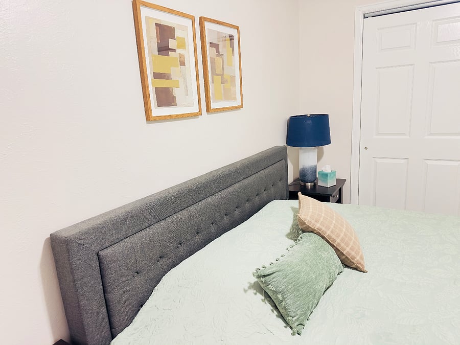Comfortable bedroom with a plush upholstered headboard, soft bedding, and cozy accent pillows. Nightstand includes a built-in charging station and lamp, creating a convenient and relaxing space for a restful nights sleep.