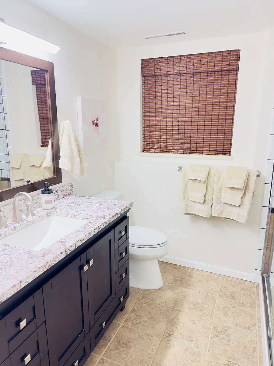 Full bathroom with a granite countertop, modern sink and fixtures, and a large mirror. Clean, bright space with fresh towels and a tiled shower, designed for comfort and everyday convenience.