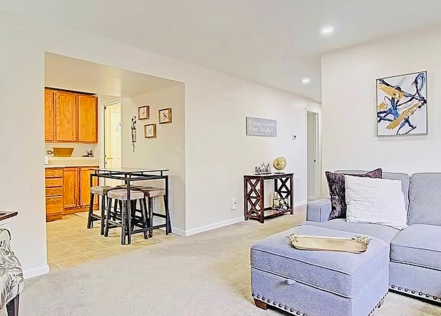 Bright and comfortable living room with an open layout, cozy seating, and plenty of natural light. The space flows seamlessly into the dining area and kitchen, making it perfect for relaxing, entertaining, or enjoying time at home.