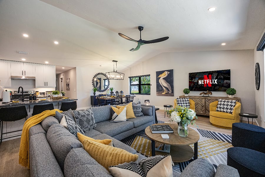 Bright living room with a large sectional and smart TV. Seamless flow to the renovated kitchen with a breakfast bar for four and a dining table for six. Perfect for families and groups.