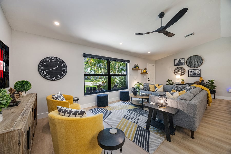 Spacious open-concept living room with a large sectional, swivel chairs, and ottomans. A cozy spot for coffee, reading, board games, or just hanging out.