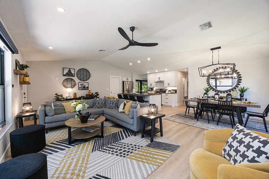 Main living room with a roomy sectional, wall-mounted smart TV, and a vaulted ceiling. Airy, comfortable space for family movie nights and relaxing together.