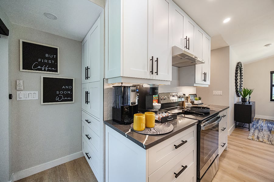 Range with hood, plenty of cabinet storage, and the coffee setup beside the stove for quick mornings.
