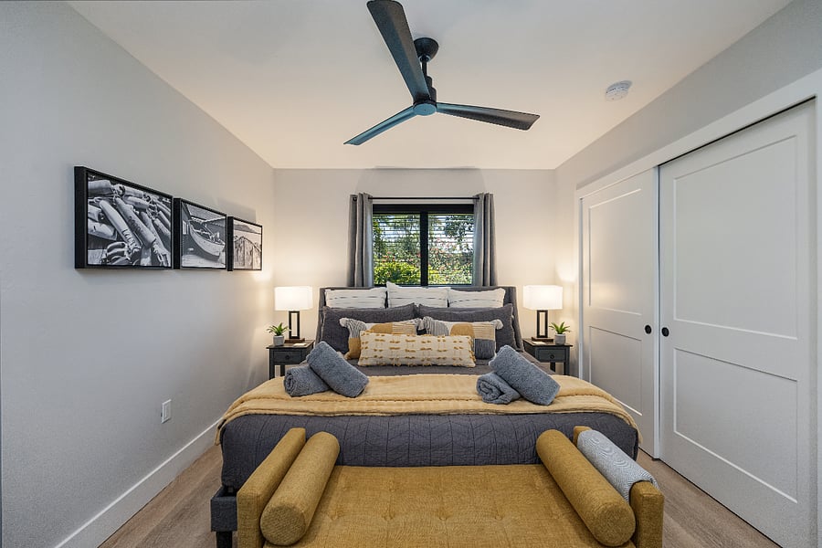 Front view of the king bed with bedside lamps and soft lighting. Sliding closet doors offer easy storage.