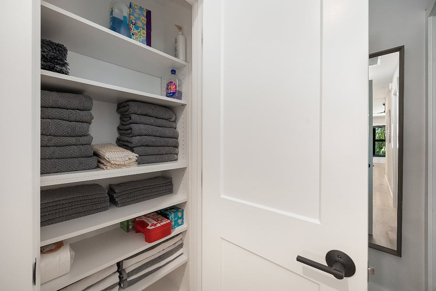 Hall closet stocked with bath towels, hand towels, washcloths, extra blankets, paper goods, and a first-aid kit.