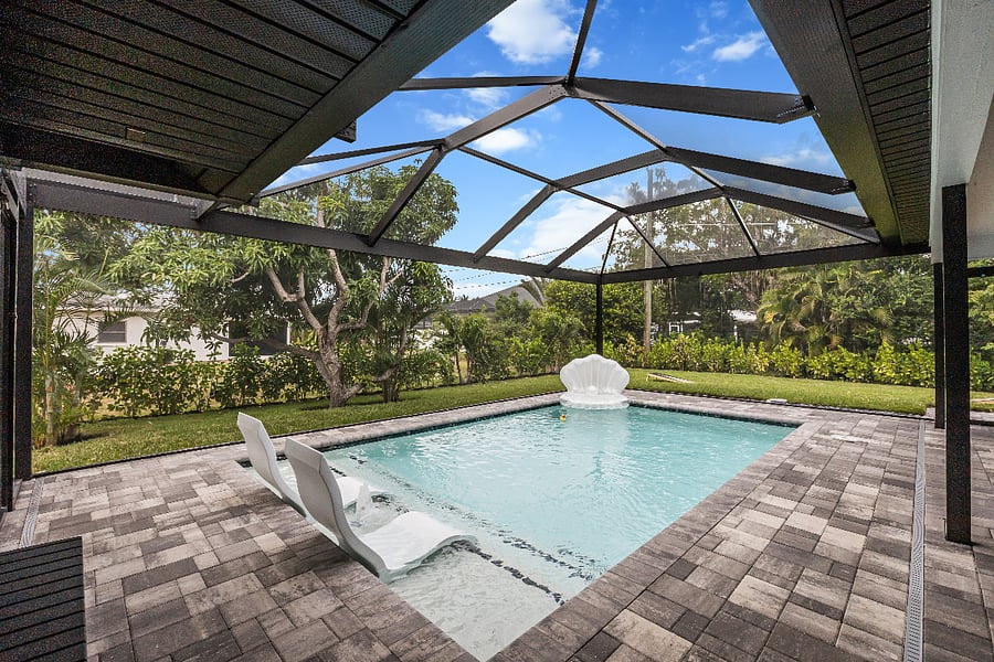 Relax in style in your screened-in pool oasis, complete with in-water loungers and surrounded by tropical greenery for the perfect blend of comfort and privacy.
