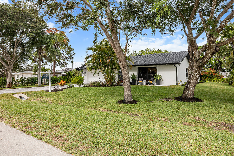 Enjoy the privacy and space of a beautifully landscaped lot with mature trees and a welcoming front patio perfect for relaxing under the Florida sun.
