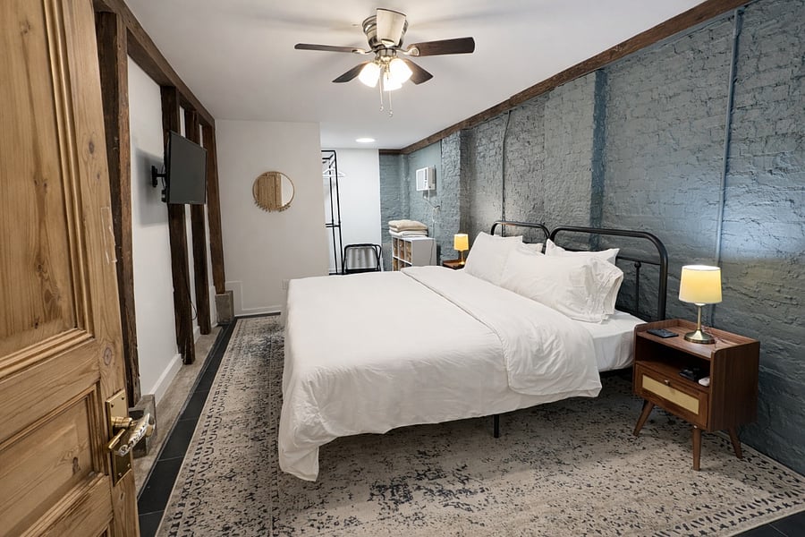 Rear Bedroom that is located behind the kitchen has a king bed that has a medium feel, open closet/storage, and Wall mounted TV. 