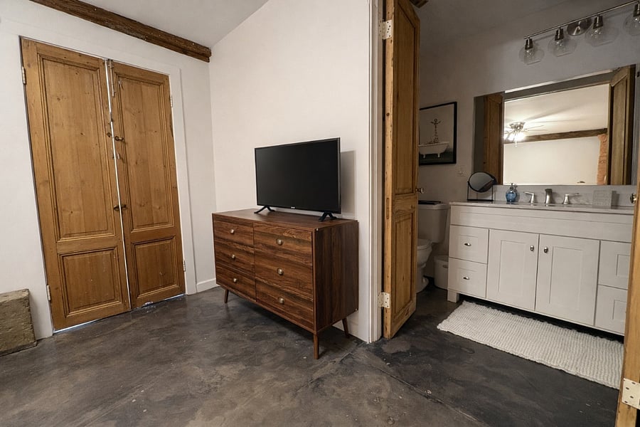 Queen bedroom has a tv and dresser for storage.