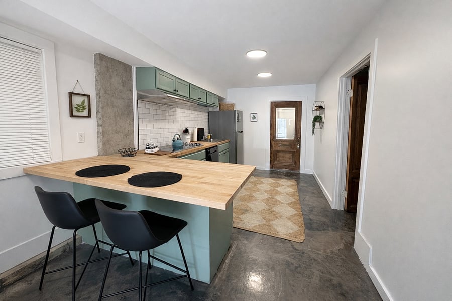 This kitchen has everything you need- electric cooktop, dishwasher, full fridge, airfryer/toaster oven, blender, bar area for prepping food, vent exhaust, fire extinguisher, plates, bowls, pots, pans, Tupperware, silverware, wine glasses, and kettle. To the right you will find the 1st bedroom that has a queen bed and private bath.