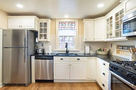 The kitchen with microwave, fridge, and gas stove. 
