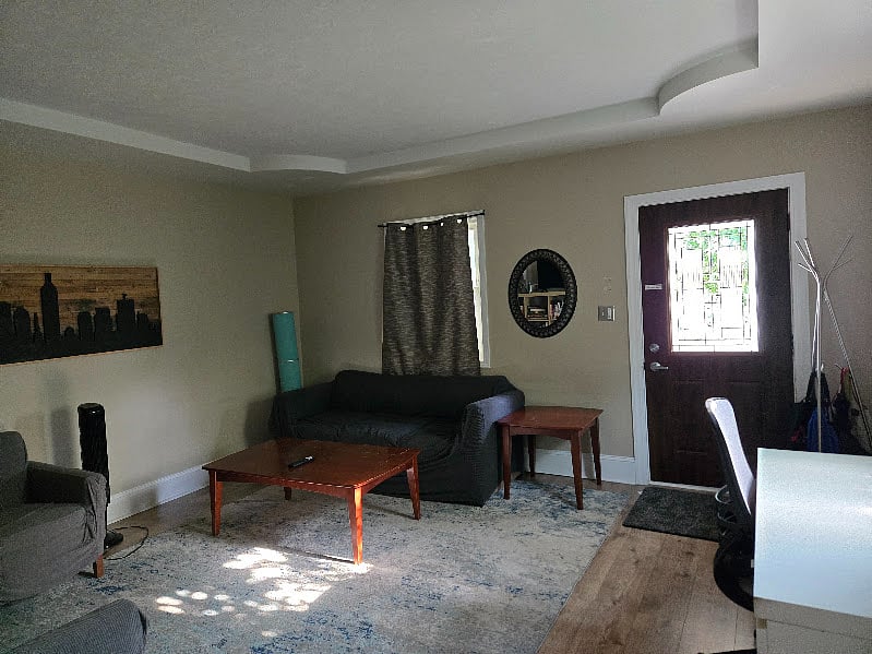View of the front door and living room from the hallway. 