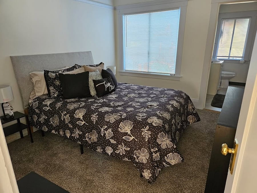 Cozy furnished bedroom with queen bed and storage.