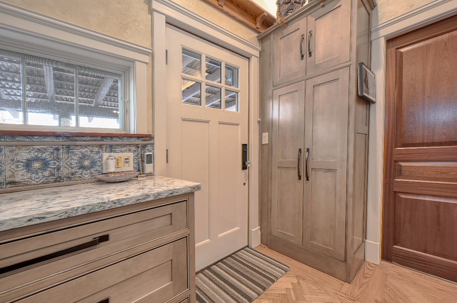 A side pantry holds additional kitchen appliances and glassware storage containers. The door next to pantry accesses the bedroom. 