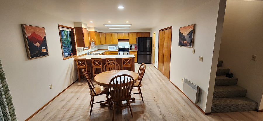 View of the fully stocked kitchen, large fridge, dishwasher, microwave, electric stove and countertop bar space.
