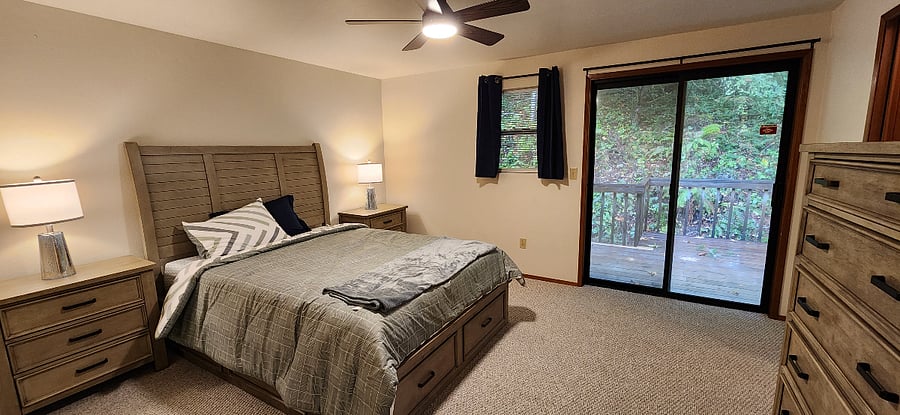 Upstairs master. Queen size bed, walk in closet, tall armoire, full bathroom with two sinks and tub. View of sliding door to private deck.