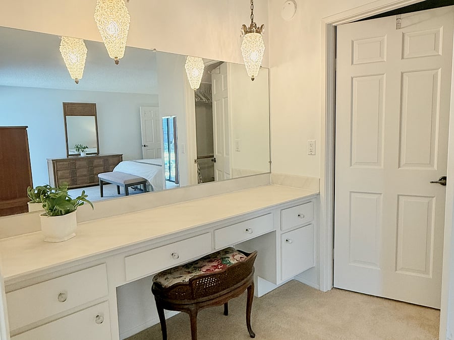 Vanity in the primary bedroom with a large walk-in closet to the right and the bathroom to the left.