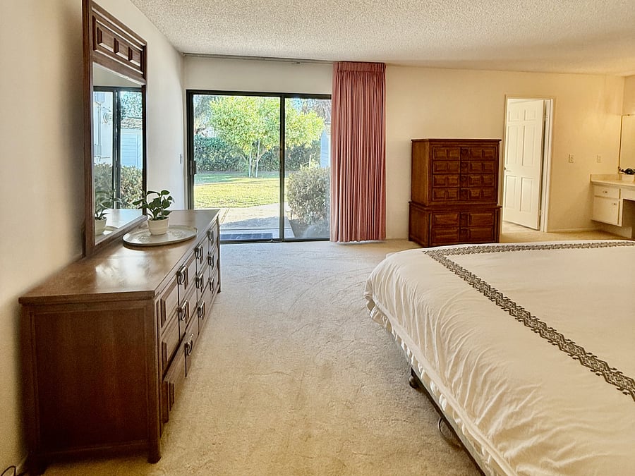 Primary bedroom has room darkening curtains and sliding glass doors to the patio.