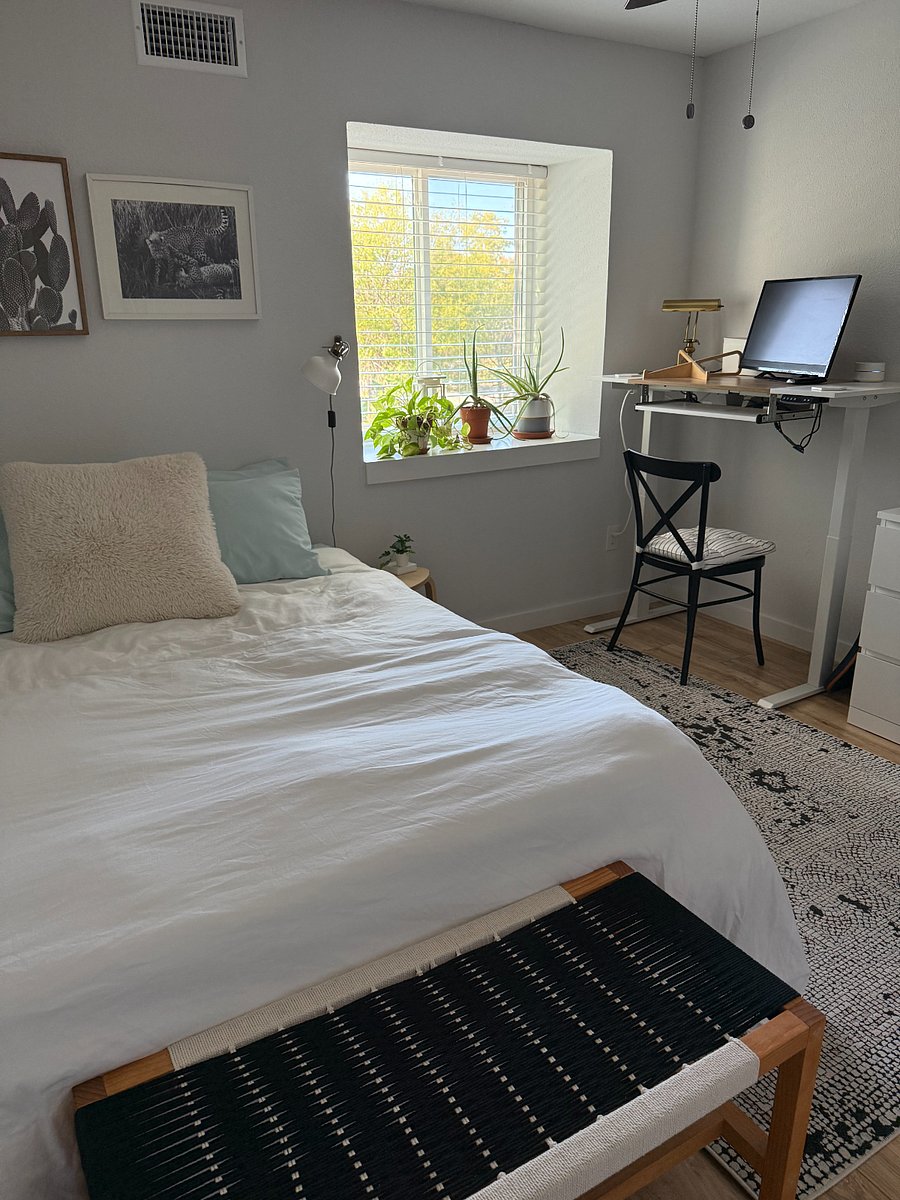 Guest room has a queen bed and an electronic standing desk.
