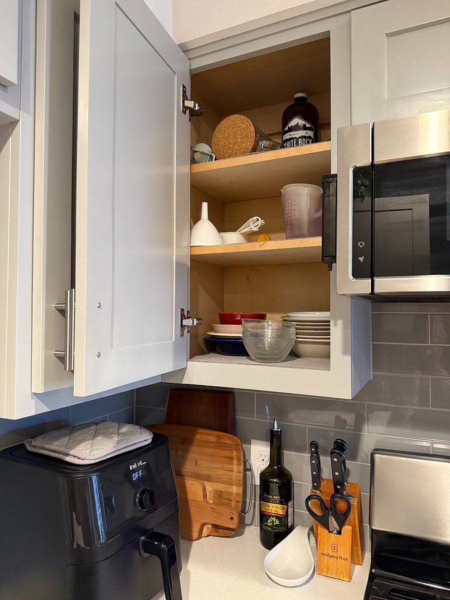 Fully stocked kitchen with plates, bowls, cups.