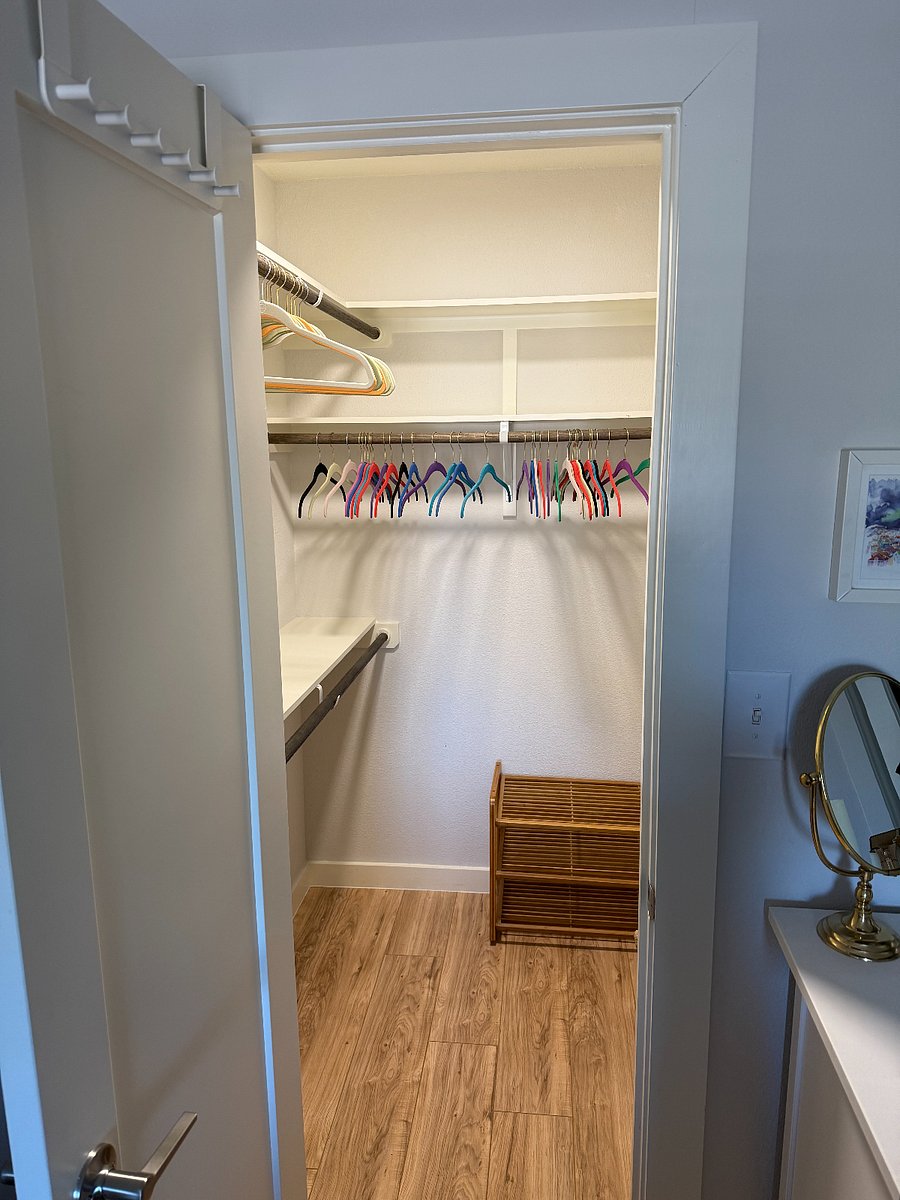 Primary walk-in closet with lots of hangers and a shoe cabinet.