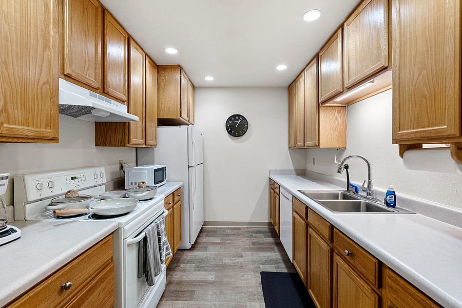 Full, brightly lit kitchen with electric stove, dishwasher, fridge, microwave, toaster and coffee maker