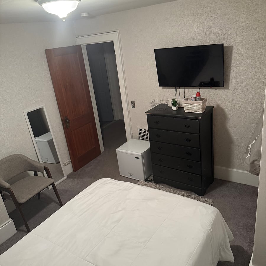 Smaller bedroom with full size bed and mounted smart TV