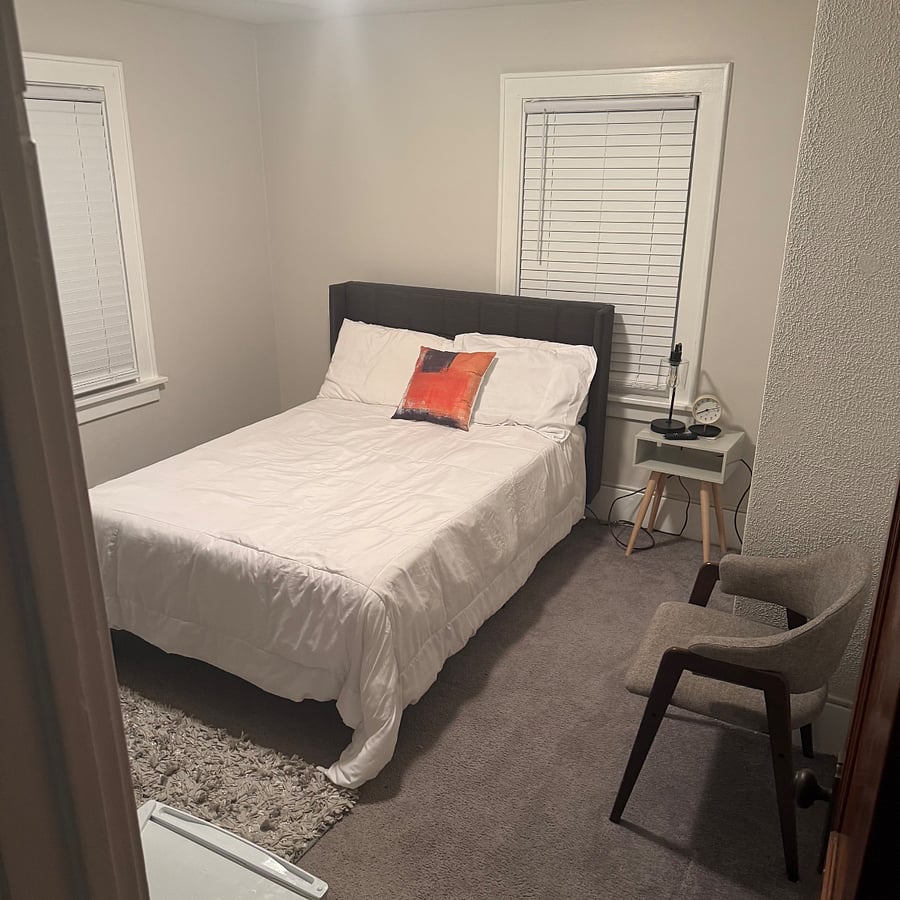 Smaller bedroom with full size bed and mounted smart TV