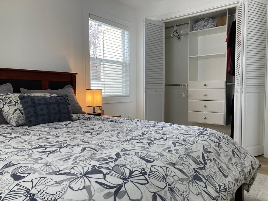 First bedroom with large closet with built in dresser, hangers, and laundry basket
