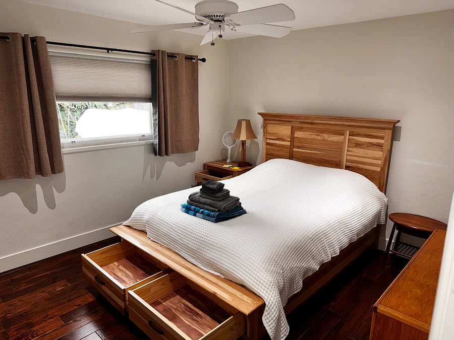 Gardenside bedroom has light-blocking window coverings, custom built in cabinets on glides, bookshelves, and a custom hickory and cedar bed.