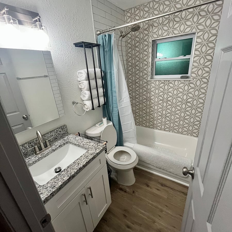 full bathroom with detachable shower head and vanity mirror with medicine cabinet for additional storage.