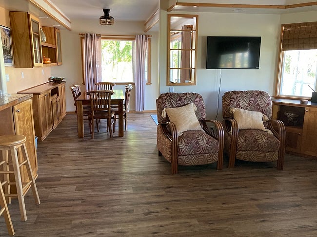 The entry is to the right of the dining table. The Smart TV is above the two recliners facing the love seat across the living room.