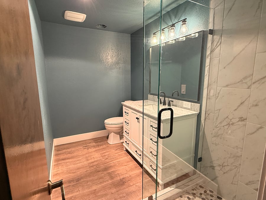 Newly remodeled lower bathroom features single vanity, roomy custom glass shower.