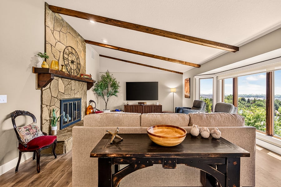The spacious main living room features vaulted ceilings, exposed wood beams, a stone fireplace, and panoramic Treasure Valley views. Comfortable seating, abundant natural light, and a 75-inch Smart TV create the perfect space to relax, connect, or unwind after a busy day.