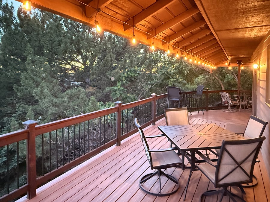 As evening falls, the expansive upper deck becomes an inviting outdoor living space. Featuring ambient caf lighting, a dining table for four, two intimate cocktail seating areas, and a Weber gas grill, it's the perfect place to enjoy dinner, conversation, and the peaceful beauty of Boise's wooded foothills.