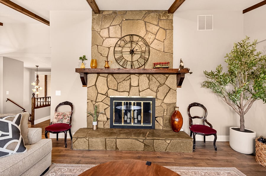 A dramatic floor-to-ceiling natural stone fireplace with a handcrafted wood mantel creates a warm architectural focal point in the main living room. Combined with vaulted ceilings, exposed wood beams, and abundant natural light, it gives the home a welcoming mountain-lodge feel while overlooking the Treasure Valley.