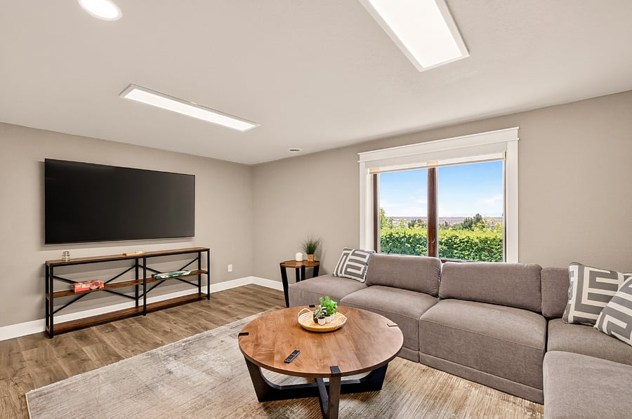 Lower level family room with 75" Samsung smart TV, sectional sofa and fireplace.