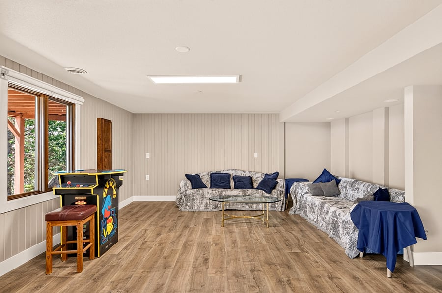 Lower level game room with sitting area and the first (of many) games: classic PacMan arcade console + 14 other 80s favorites