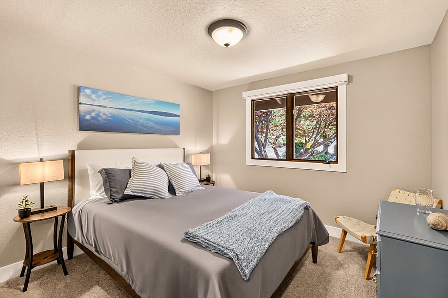 Comfortably furnished with a queen bed, dresser, full closet, and cozy sitting chair, this inviting main-level bedroom offers a quiet retreat with peaceful views of the mature trees just outside the window. Thoughtfully designed for comfort during extended stays