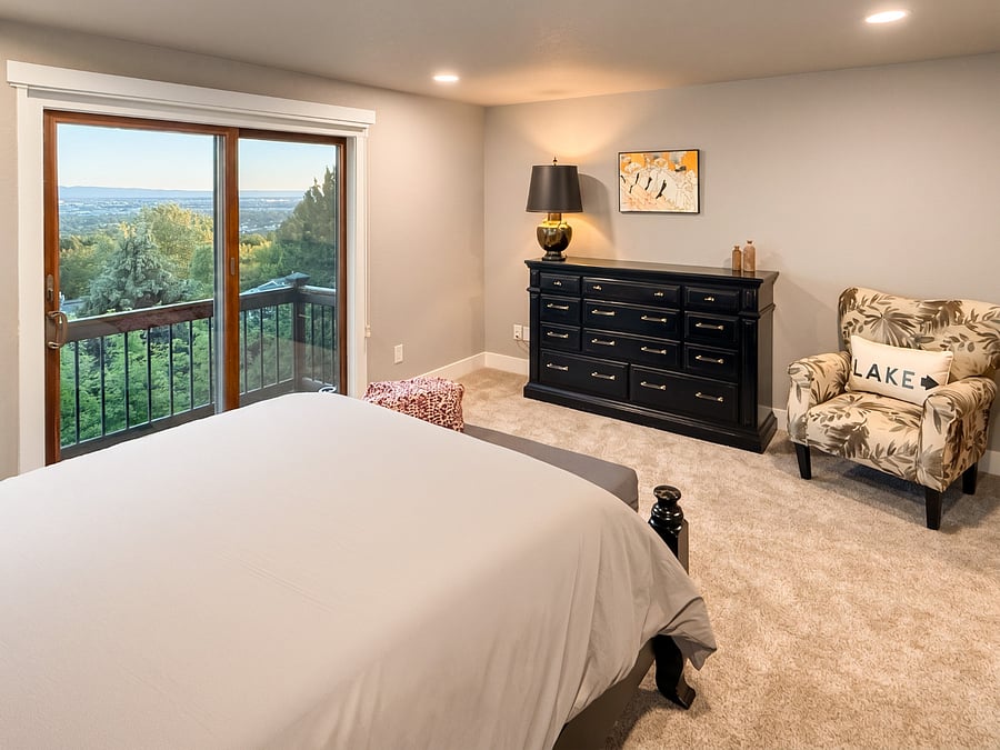 The spacious primary suite on the main level is a peaceful retreat featuring a queen bed, comfortable reading chair, and sliding glass doors that open to a private standing balcony overlooking the Treasure Valley. Start your day with fresh mountain air or unwind in the evening while taking in the panoramic views.
