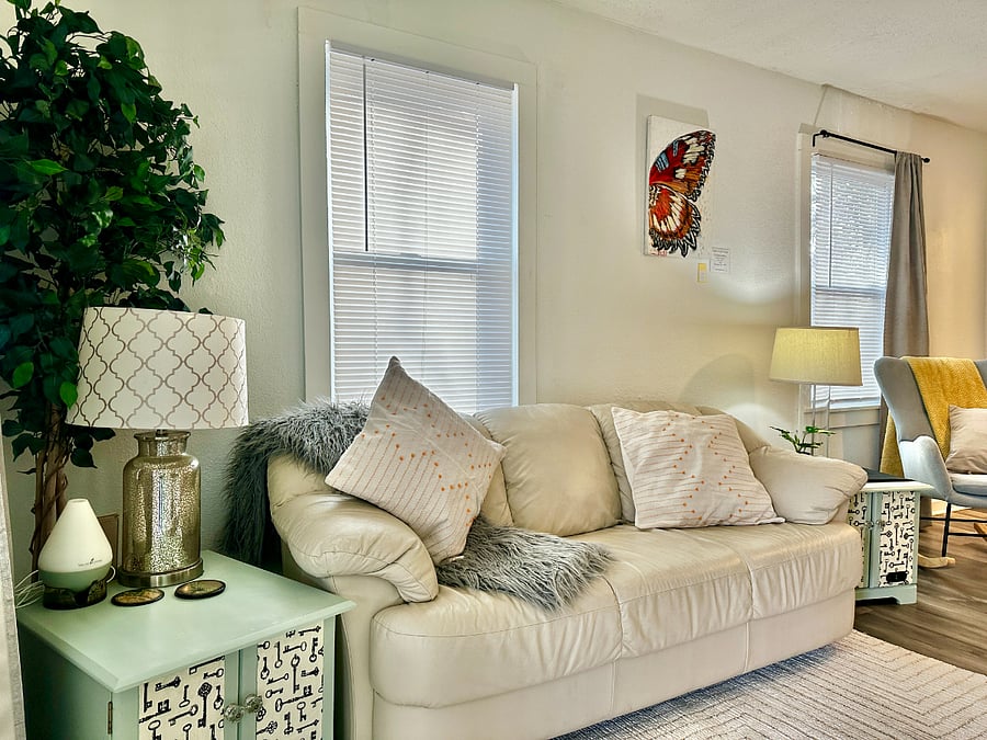 Couch & sitting area in the front room with multiple windows for natural light. 